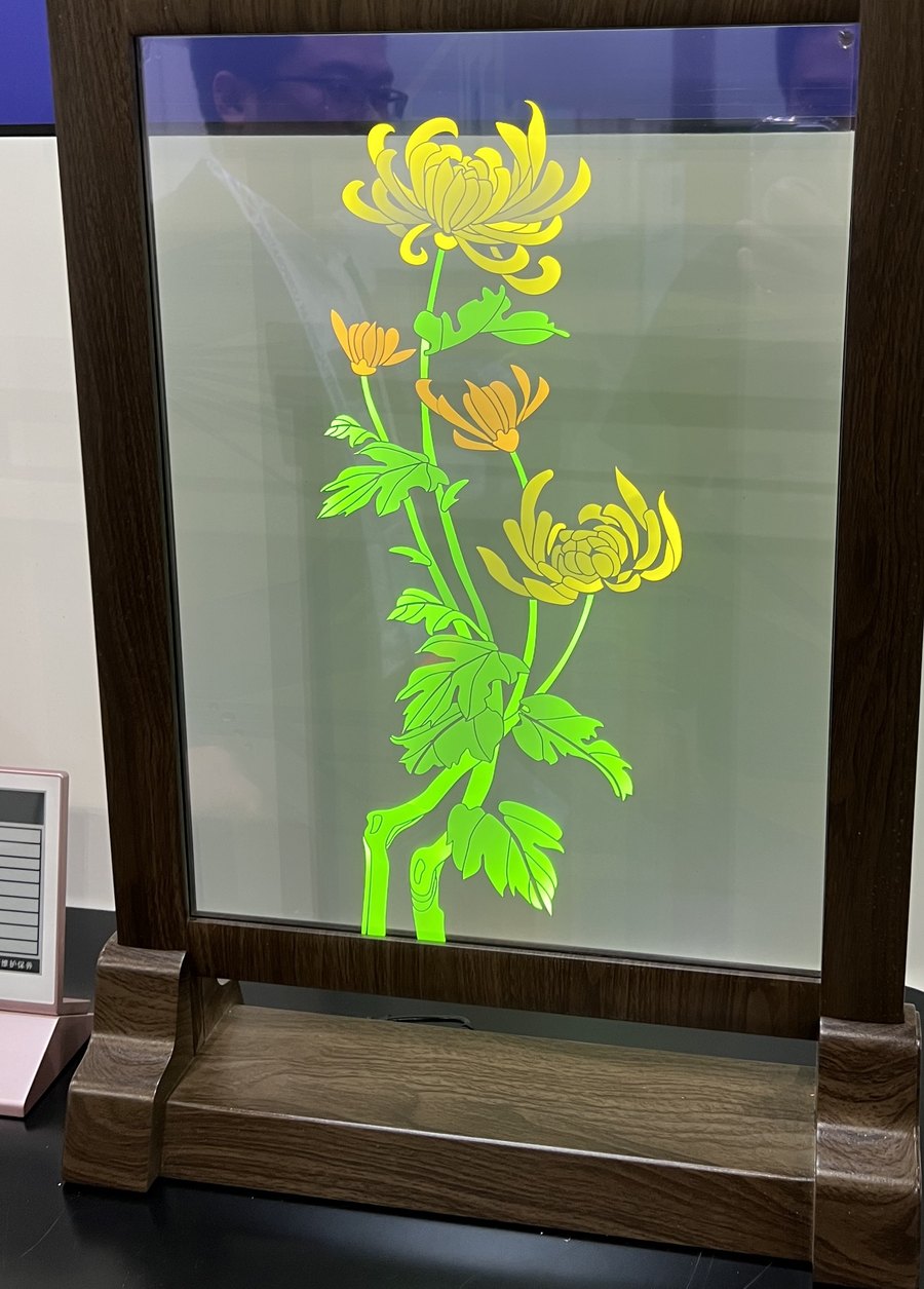 Transparent OLED panel showing chrysanthemums in a wooden stand
